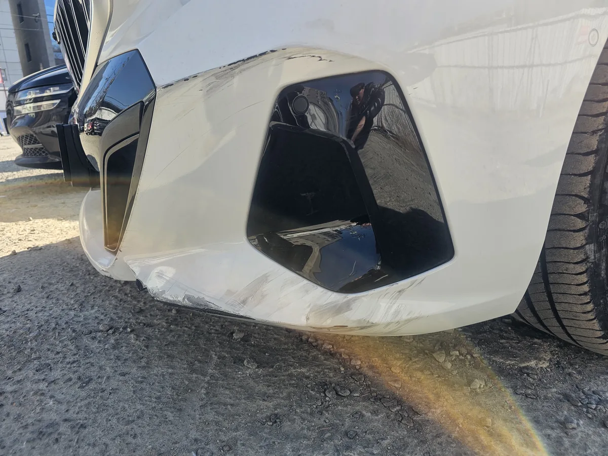 수리 전 BMW 앞범퍼의 긁힘과 도장 손상